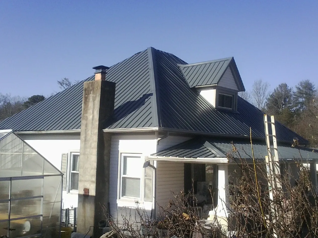 Dark blue standing seam metal roof on a white farmhouse with dormer — Slate & Tile Roof Repair by Roofing Brothers in Good Hope