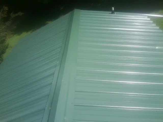 New green metal panels meeting at the ridge of a roof — Flat Roof Repair work by our crew in Good Hope