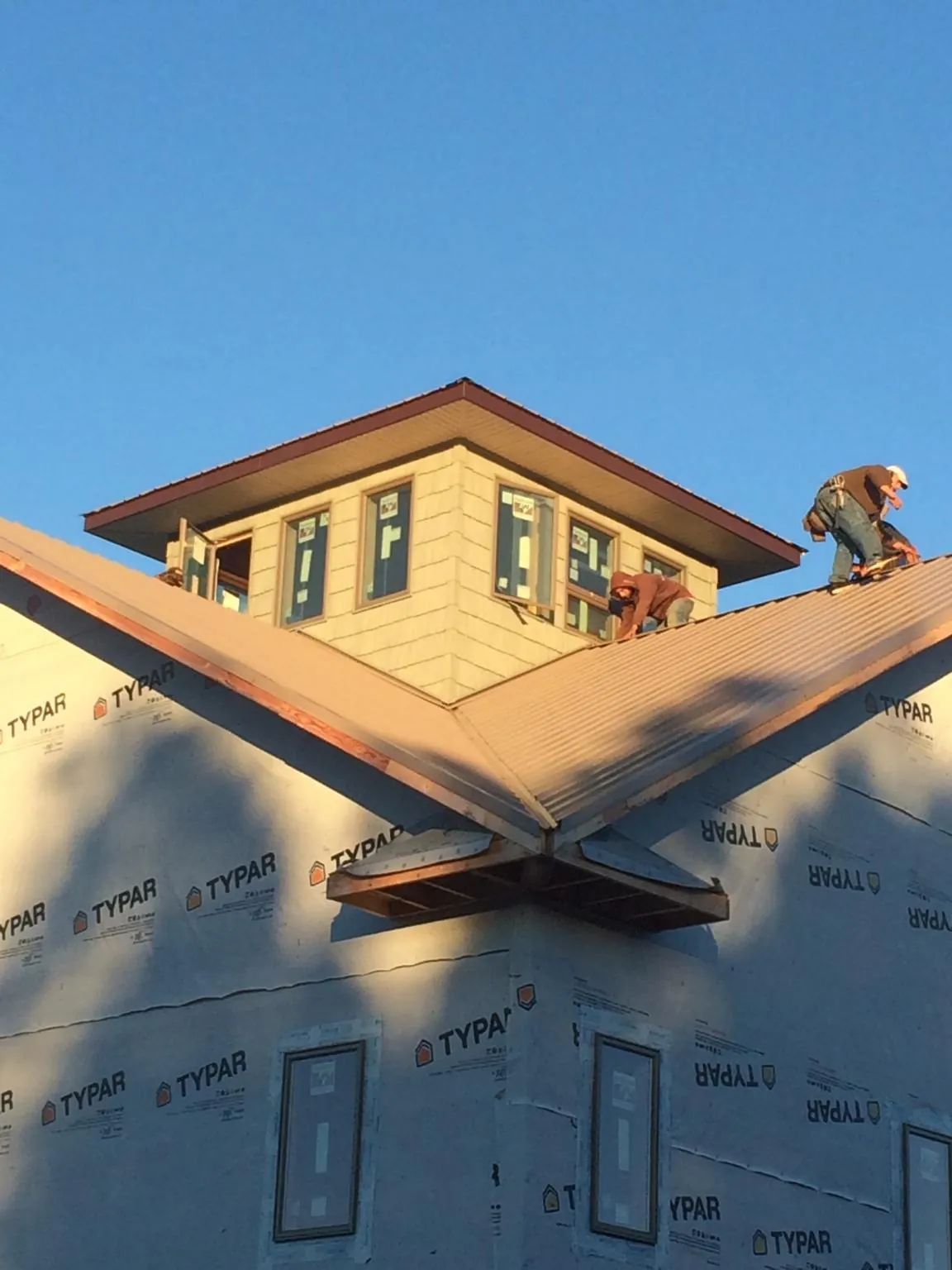 Roofers working around a rooftop cupola on a new metal roof at sunset — Roof Waterproofing in Good Hope by Roofing Brothers